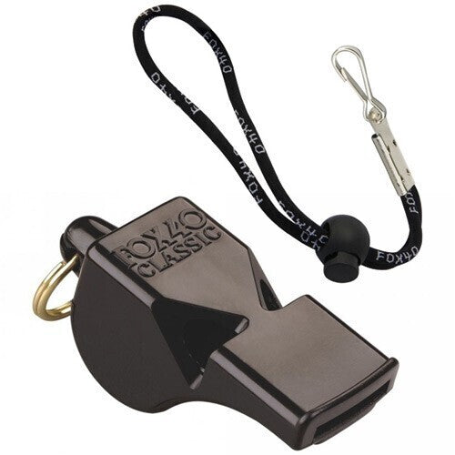 Person blowing a RoamAU safety whistle in a forest; close-up of a compact RoamAU emergency whistle